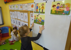 Dziewczynka zawiesza na tablicy ilustracje prezentującą jedną z zasad Kodeksu dobrych relacji.